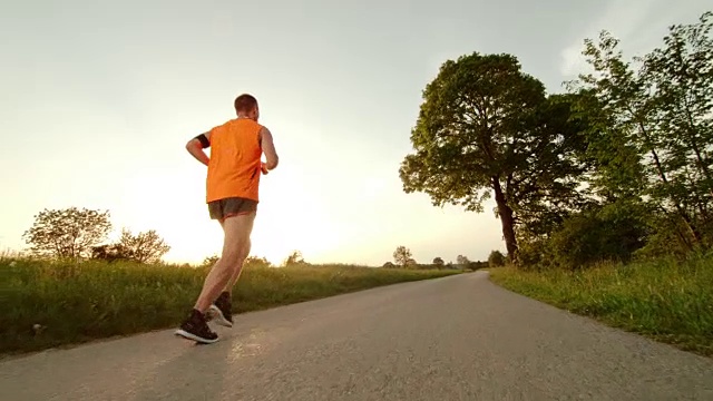 SLO MO TS男性跑步者在日落时穿过乡村视频素材