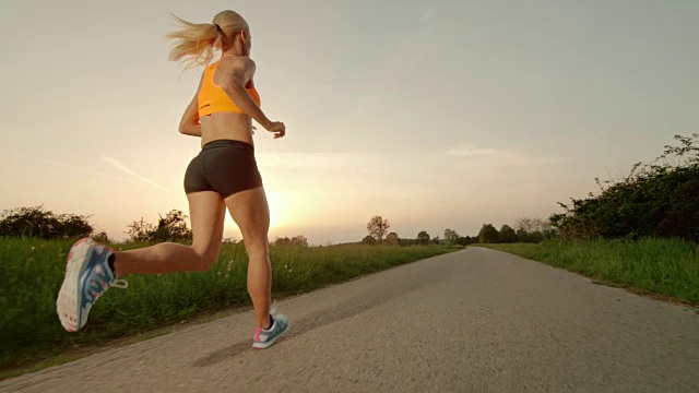 SLO MO TS金发女人在夕阳下奔跑视频素材