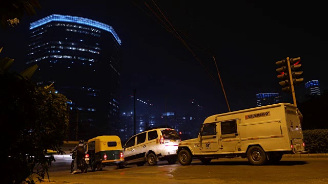 时间在夜晚流逝，古尔冈一个繁忙的十字路口，后面是高层建筑视频素材