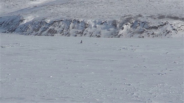 雪地摩托穿越结冰的河流视频素材