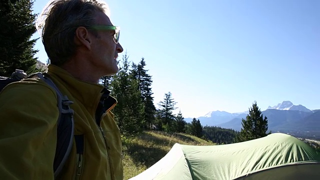 徒步旅行者在山上草地上的帐篷旁停下来视频素材