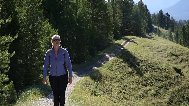 女人沿着小径远足，在山脊上拍照视频素材