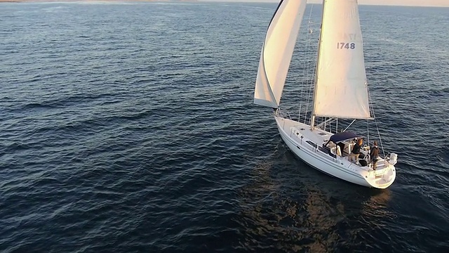 MS AERIAL POV SLO MO拍摄的帆船在海洋上航行到日落/新港海滩，加利福尼亚州，美国视频素材