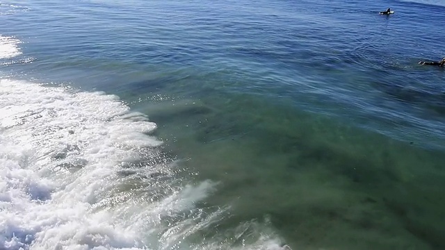 CU AERIAL POV SLO MO拍摄海浪撞击海滩和游泳的人/拉古纳海滩，美国加州视频素材