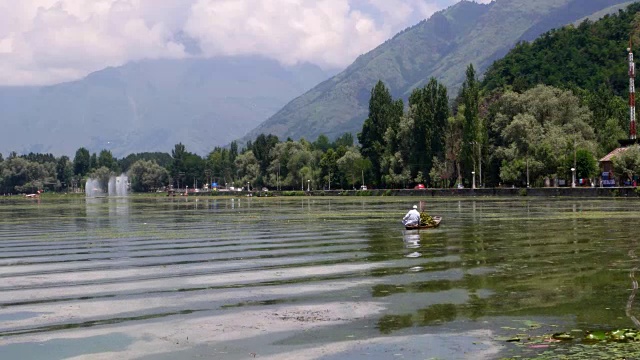 一个孤独的船夫在达尔湖上，以喜马拉雅山脉为背景，水波荡漾视频素材