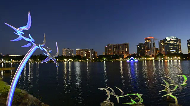 奥兰多佛罗里达湖Eola飞行浇丝布隆伯格的天际线黄昏彩色灯光与空中摩天大楼在水上的鸟雕像视频素材