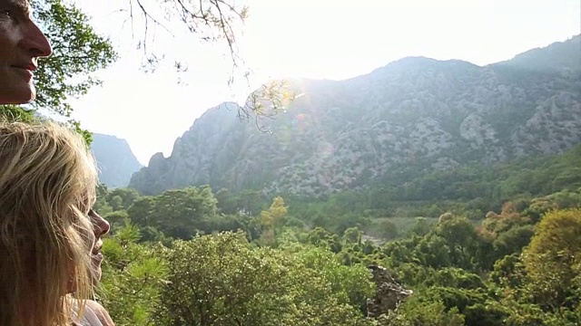 成熟的夫妇从森林的树冠看向群山，日出视频素材