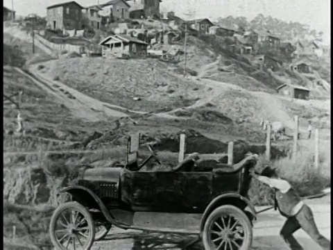 1925年，一个人(比利·比文)把车推向悬崖边缘/房子+马的背景/特写视频素材