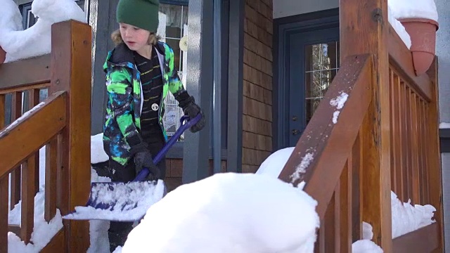 小男孩高兴地铲掉门廊上的雪视频素材