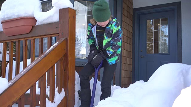 小男孩高兴地铲掉门廊上的雪视频素材