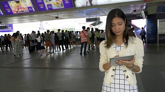 一名女子在轻轨站使用平板电脑视频素材