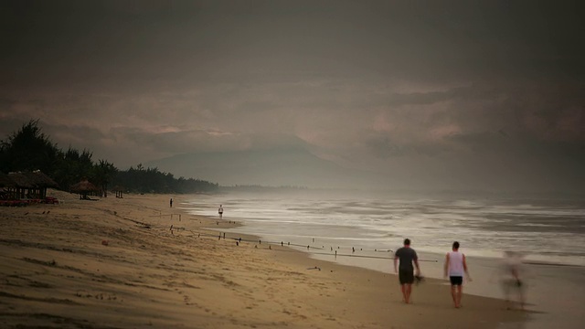 WS T/L ZO View of People coming and going in ebb and flow of waves over sand with mist distance /会安，越南视频素材