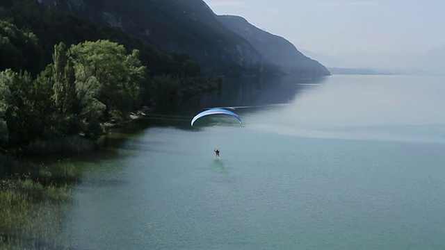 WS SLO MO空中Paramotor飞行和触摸一个湖与他的脚在法国阿尔卑斯山/ chambery, savoir，法国视频素材