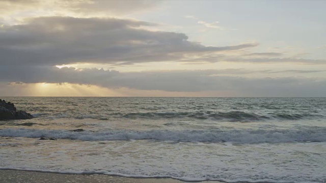 太阳落山时，小波浪冲上海滩视频素材