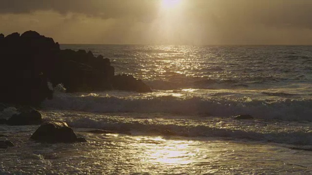 太阳落山时，海浪冲击着岩石视频素材