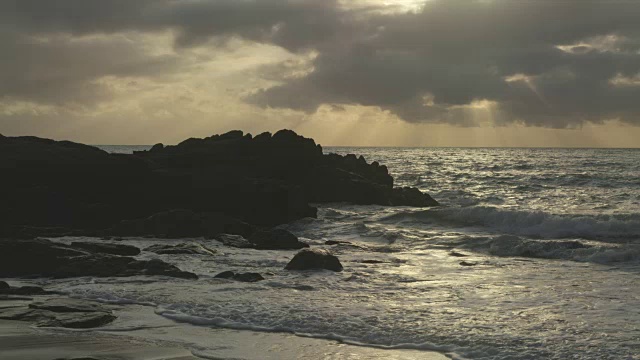 太阳落山时，海浪冲击着岩石视频素材