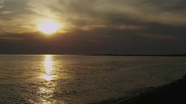 科德角的鲱鱼湾，海面上金色的日落，背景是一座灯塔。视频素材