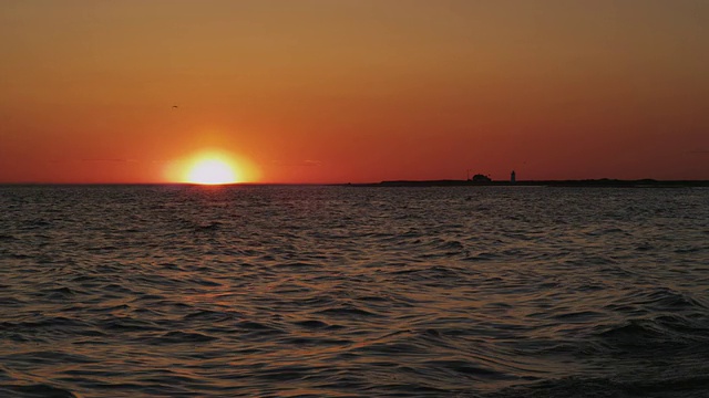 鳕鱼角鲱鱼湾的橙色日落，海鸟和灯塔的背景和海浪的慢镜头。视频素材