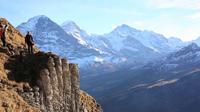 徒步旅行者爬上山谷和山脉之上的山脊视频素材