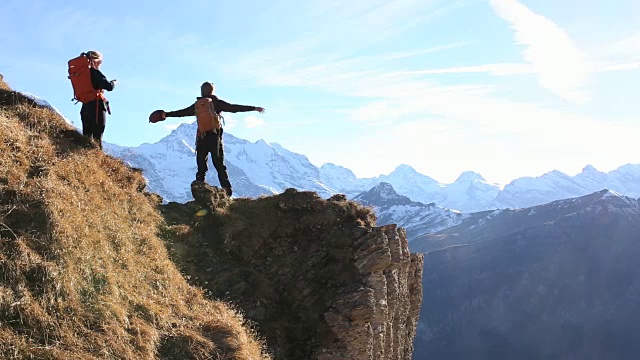 登山者在陡峭的悬崖上用智能手机给同伴拍照视频素材