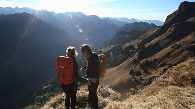 徒步旅行者到达了下面山谷的陡坡边缘视频素材