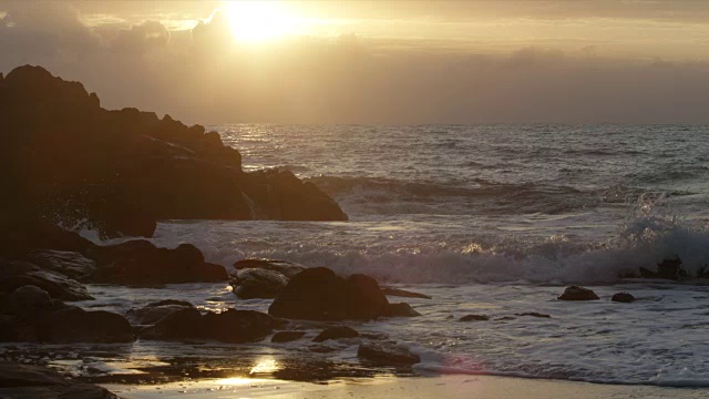 太阳落山时，海浪冲击着岩石视频素材