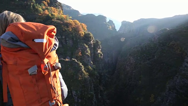 女性徒步旅行者沿着山脊行走，在峡谷之上视频素材