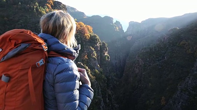 女性徒步旅行者沿着山脊行走，在峡谷之上视频素材