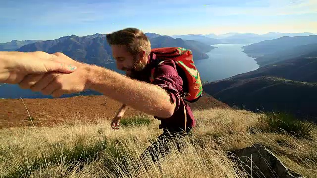 男子在困难地形上徒步旅行，伸手相助视频素材