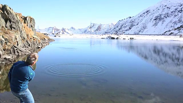 在雪山下，人们用石头跳过山池视频素材