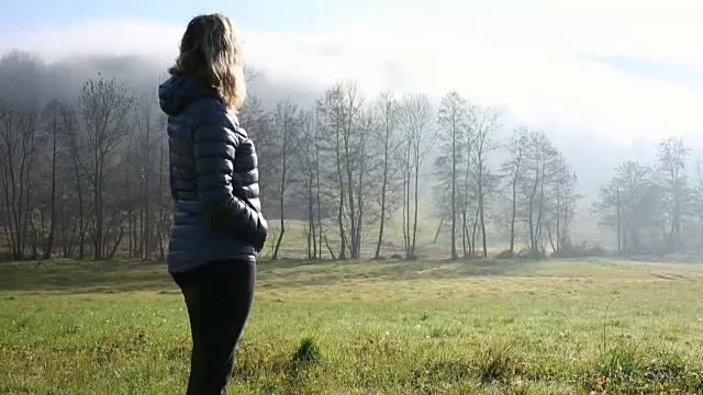 当雾滚滚而来的时候，潘向正在穿过草地的女人走去视频素材