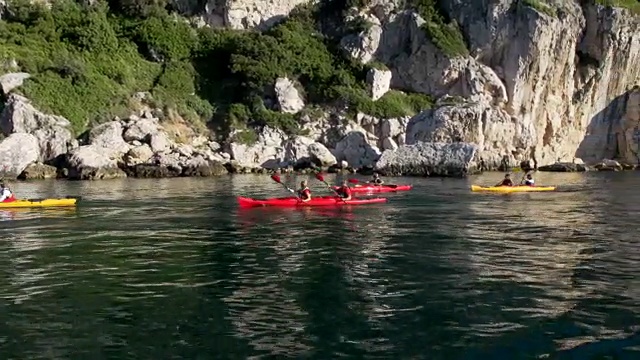 朋友们沿着岩石海岸划皮艇视频素材