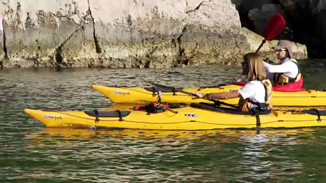 朋友们沿着岩石海岸划皮艇视频素材