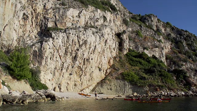 朋友们沿着岩石海岸划皮艇视频素材