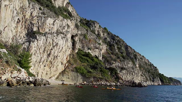 朋友们沿着岩石海岸划皮艇视频素材