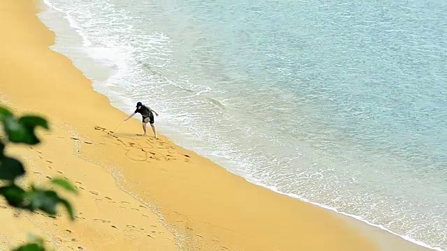 美丽的女人在海滩上画“海”字视频素材