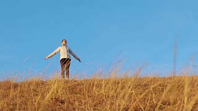 年轻女子在日落时跑上山。视频素材