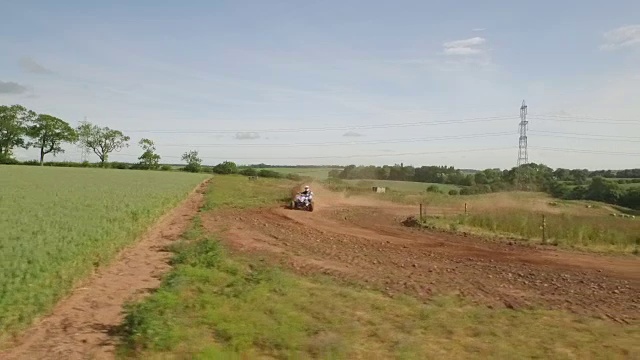 追踪无人机拍摄的四轮自行车/越野车辆在尘土飞扬的土路上视频素材