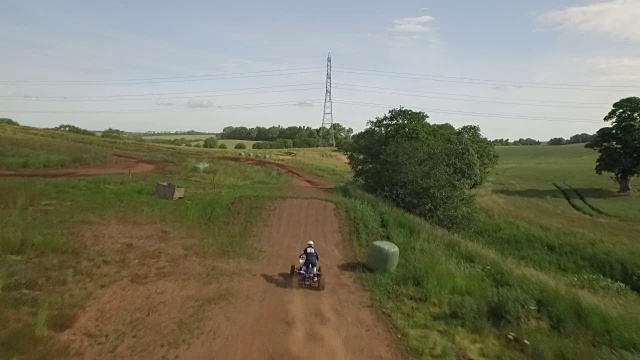 追踪无人机拍摄的四轮自行车/越野车辆在尘土飞扬的土路上视频素材