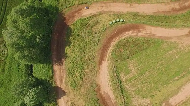 跟踪鸟瞰无人机拍摄的四轮自行车/越野车辆在尘土飞扬的土路视频素材