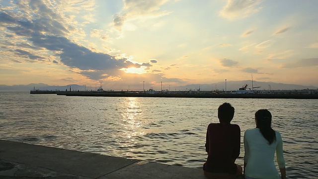 一对年轻夫妇坐在海边的WS照片/神奈川，日本视频素材