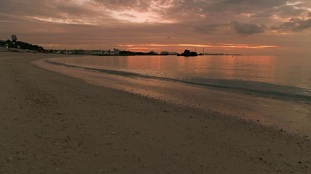 4K，近距离拍摄日落时沙滩上的海浪。视频素材