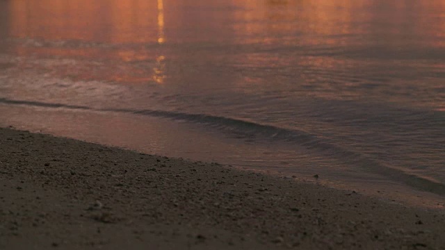 4K，近距离拍摄日落时沙滩上的海浪。视频素材