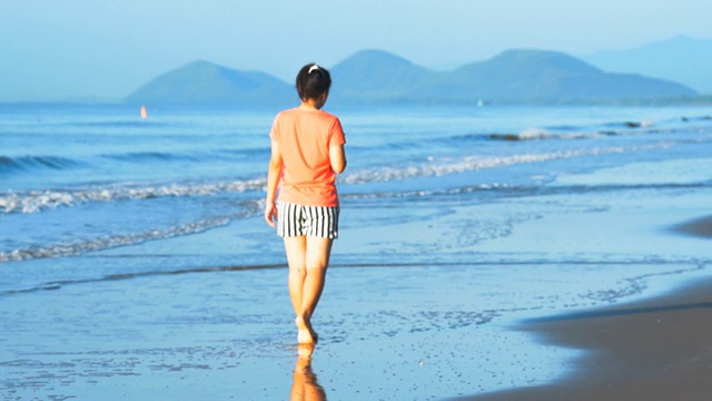 在海滩上散步的女人视频素材