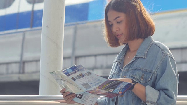 年轻女子在空中火车站拿着旅游地图视频素材