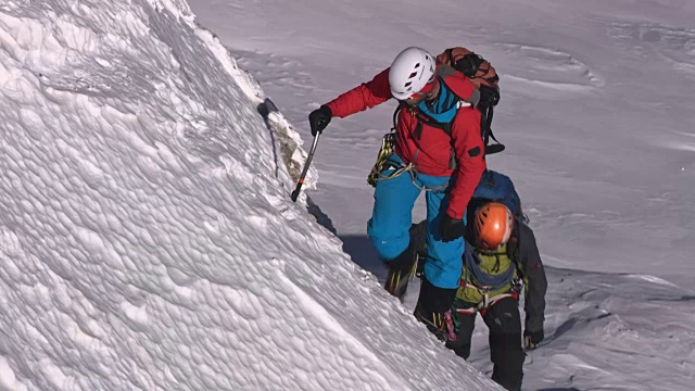 两个登山运动员正在爬雪山的斜坡视频素材