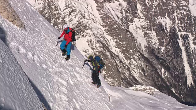 两个登山运动员正爬上陡峭的雪山边视频素材