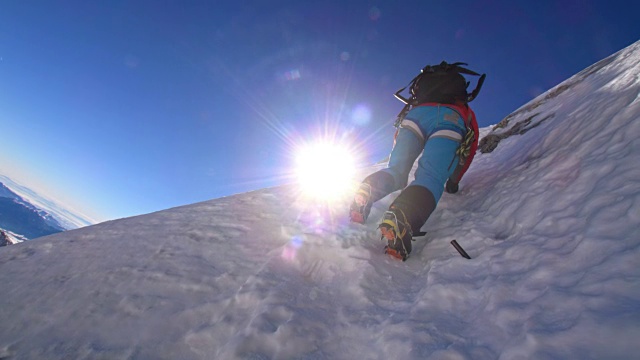 登山运动员在阳光下爬上陡峭的雪墙视频素材