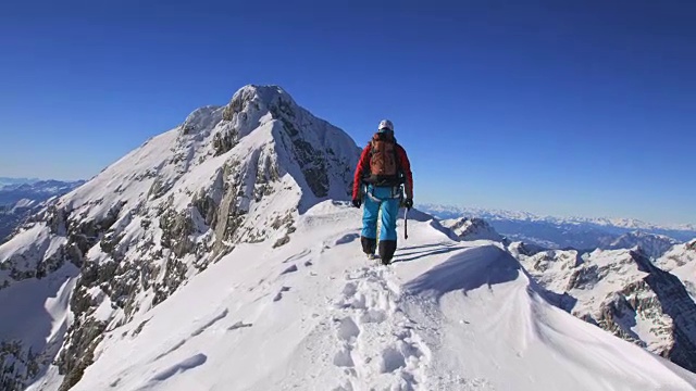 登山队员在阳光下爬上雪山脊视频素材