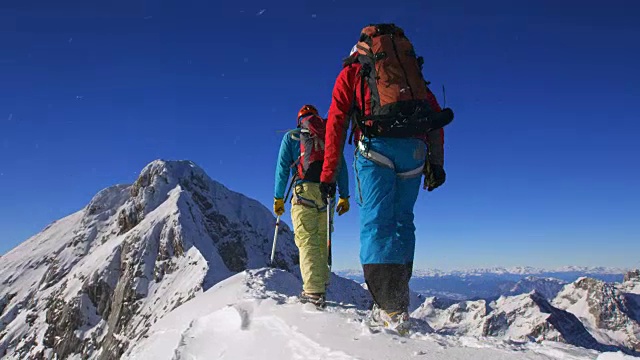 在阳光下，登山队员们正在穿越积雪的山脊视频素材